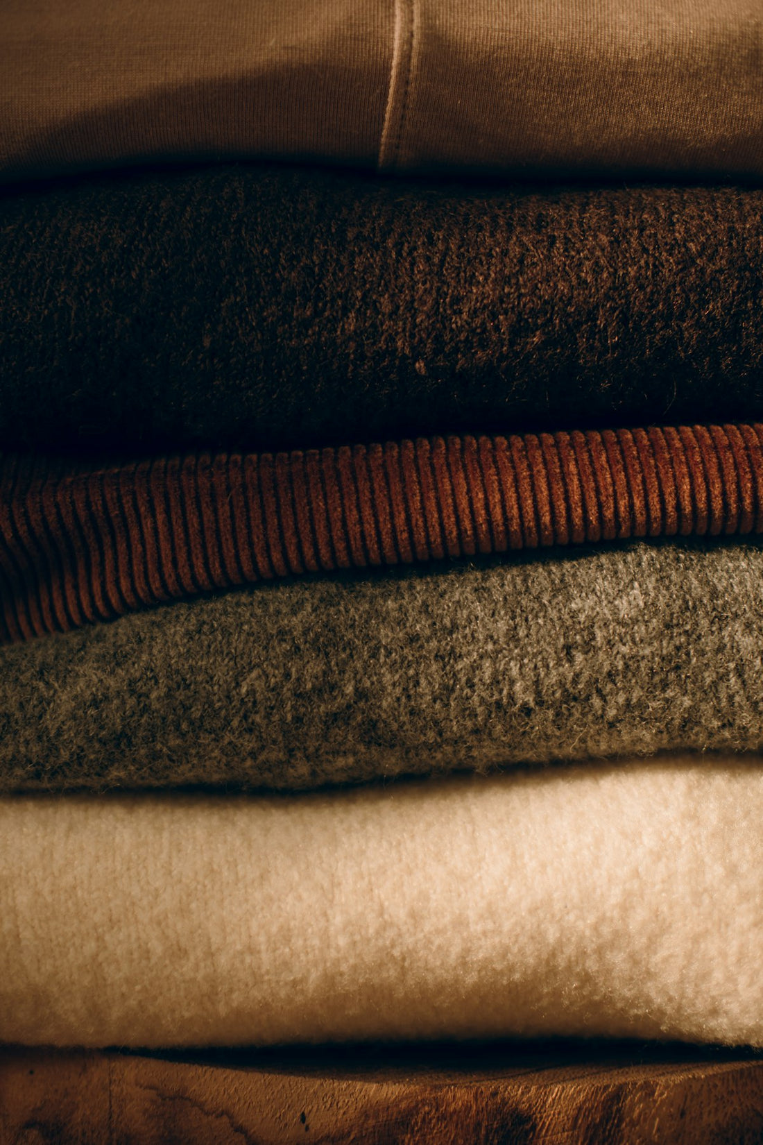 Stack of neatly folded cozy sweaters in neutral fall tones